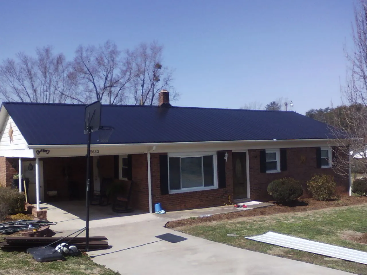 Finished dark blue metal roof on a brick ranch with a carport in Beacon Falls