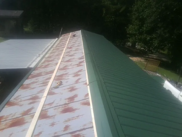 Old rusted panels beside newly installed green metal roofing — Wind Damage Roof Repair by Roofing Brothers in Beacon Falls