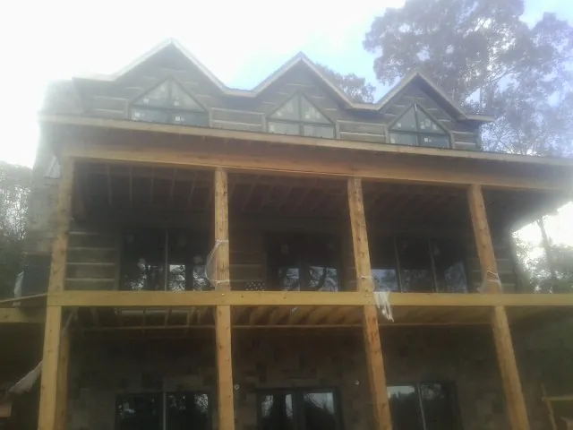 Dormers and porch framing on a large log home under construction — Roof Coating work by our crew in Beacon Falls
