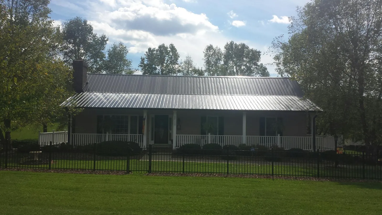 Gray metal roof on a brick ranch with a full width front porch — Gutter Guard Installation work by our crew in Beacon Falls