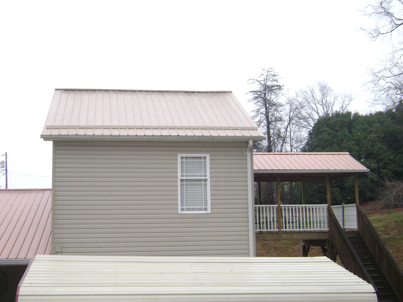 Tan metal roofs on a two story addition and attached porch, from a Roof Replacement job in Beacon Falls