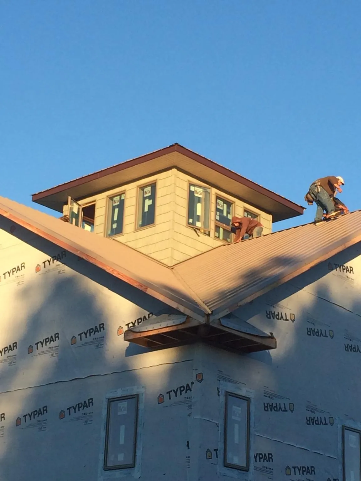 Roofers working around a rooftop cupola on a new metal roof at sunset — Roof Waterproofing in Beacon Falls by Roofing Brothers